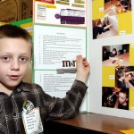 Robert Hanson, 8, explains the results of his edible chocolate melting experiment. He predicted that M&Ms would melt the slowest because of their hard candy coating. His hypothesis proved correct, but he also found that chocolate with higher coco content took longer to melt. “I love chocolate,” Hansen said when asked why he chose that experiment.